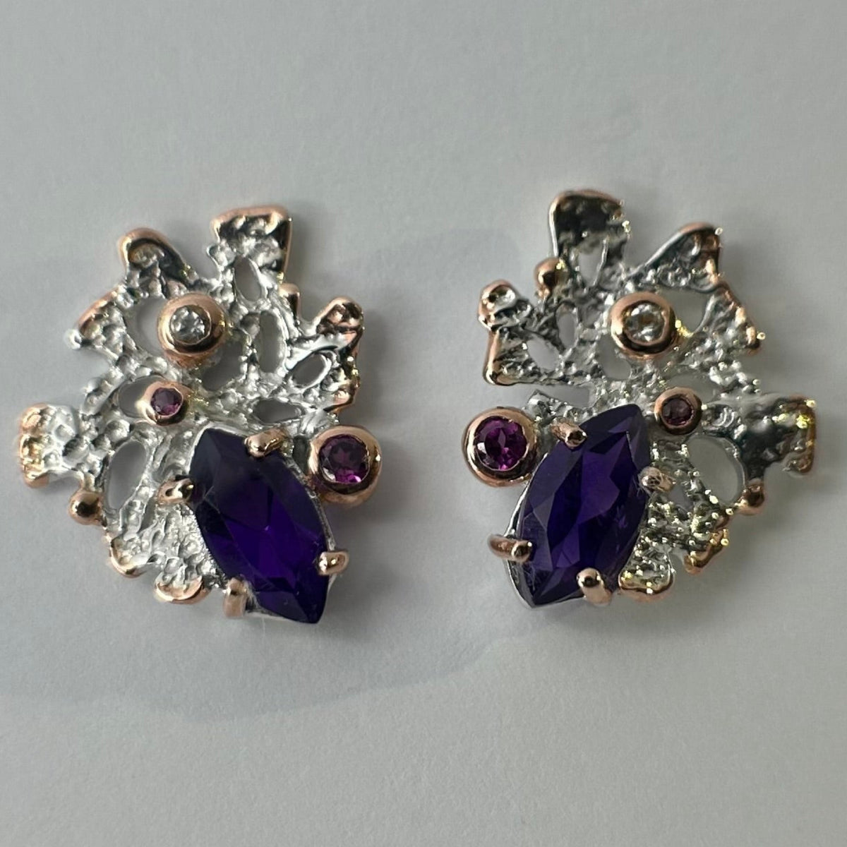 Pair of earrings with purple amethysts on a light gray background