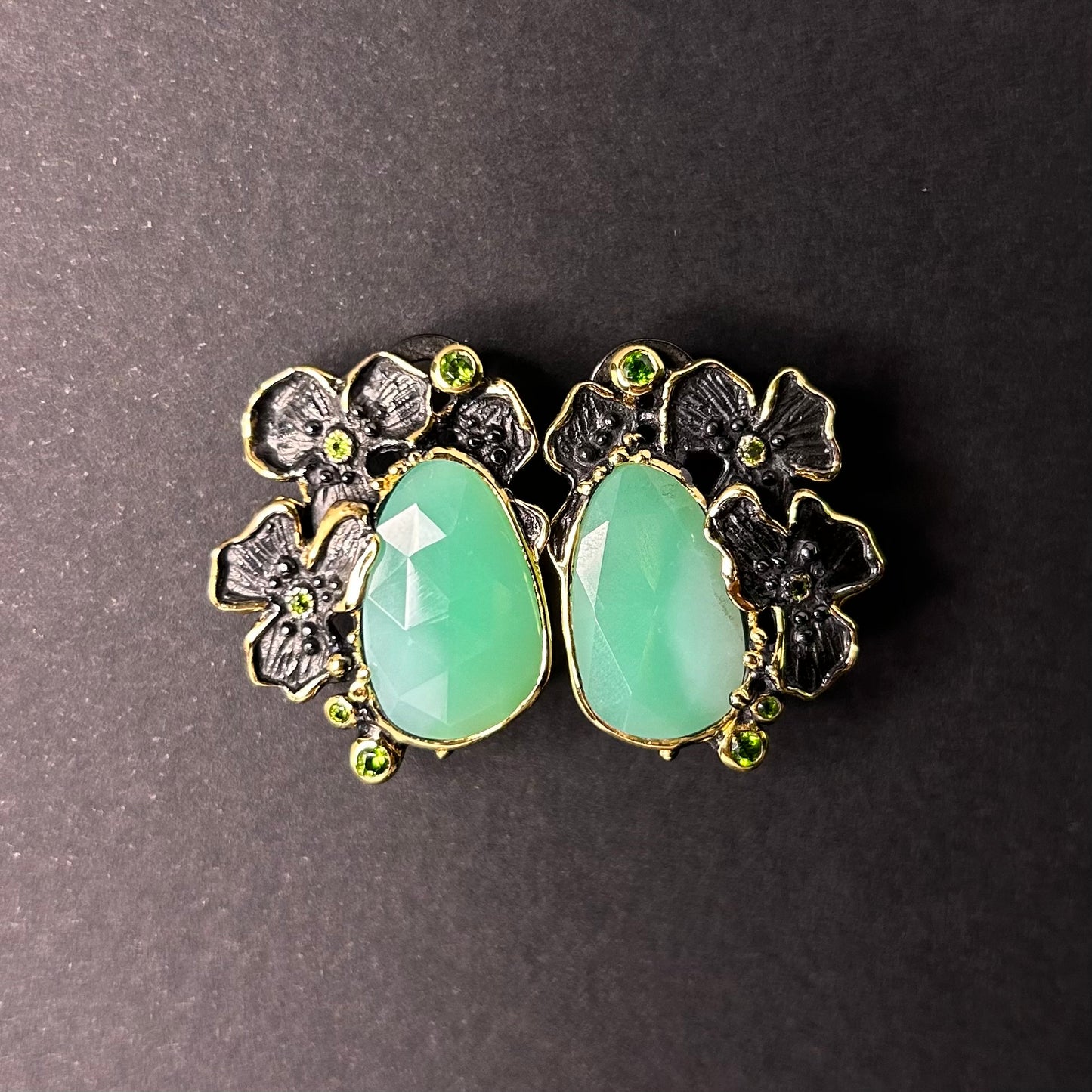 Pair of silver earrings with green chyroprase gemstones and floral designs on a gray background