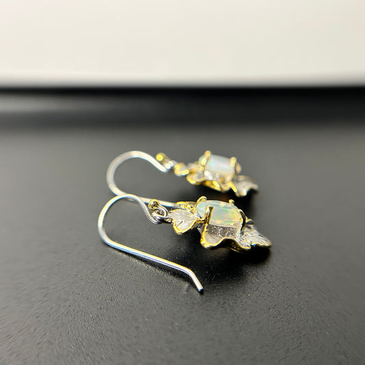 Floral earrings with Ethiopian opal stones on a black background