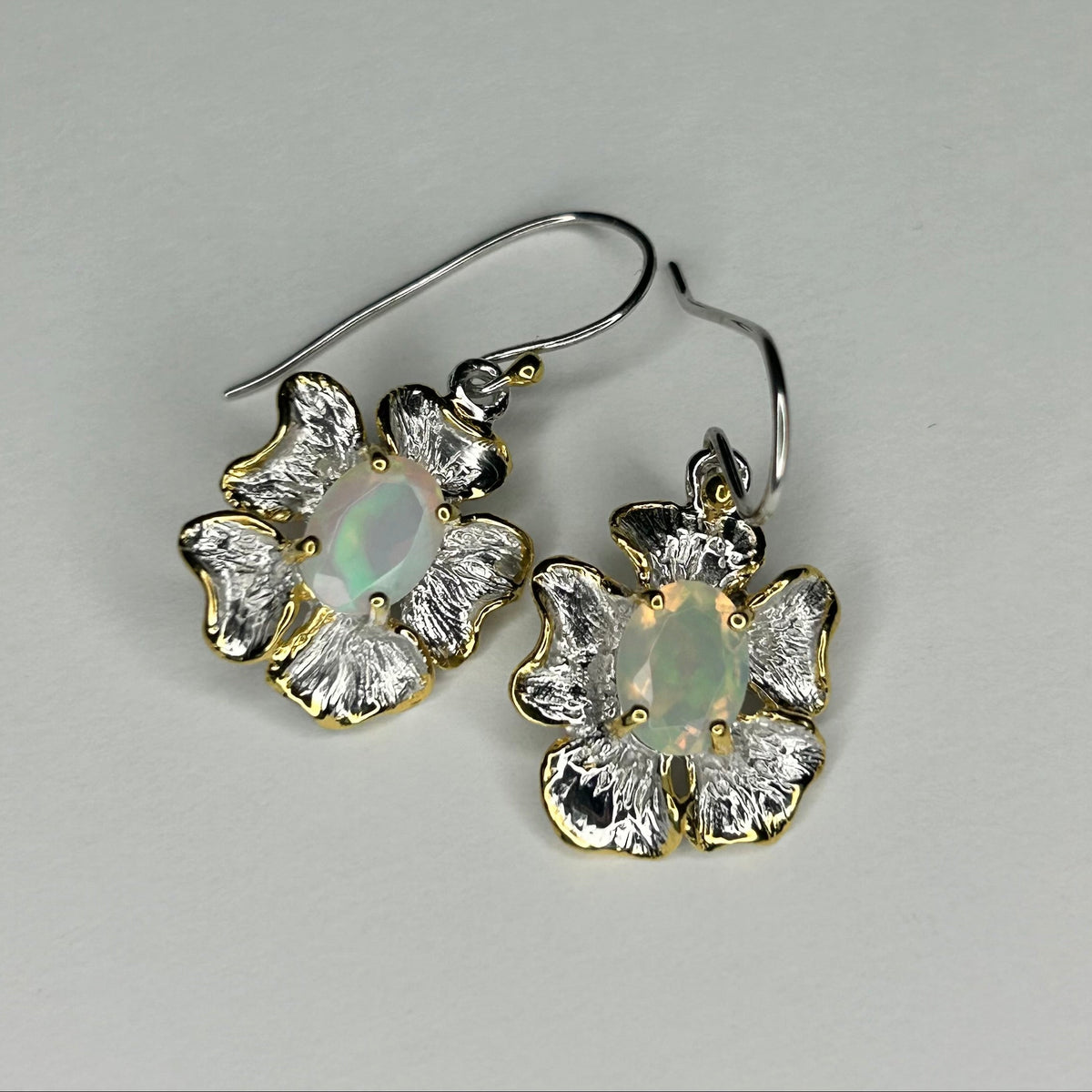 Pair of floral earrings with gemstones on a gray background