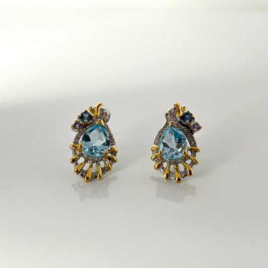 Pair of gold and topaz earrings on a light gray background