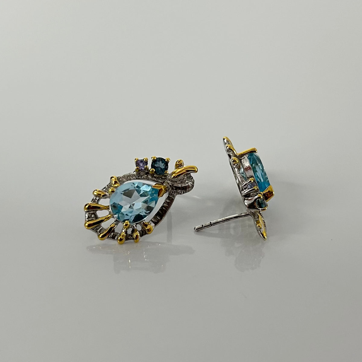 Pair of silver earrings with blue topaz on a gray background