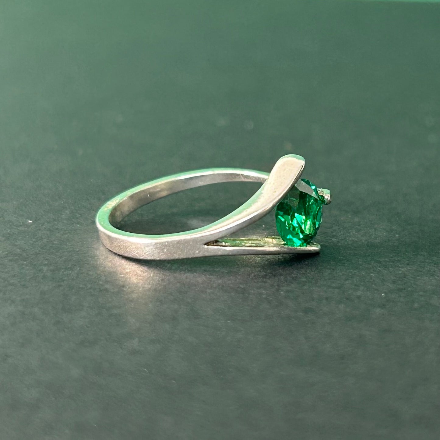 Silver ring with a green gemstone on a dark green background