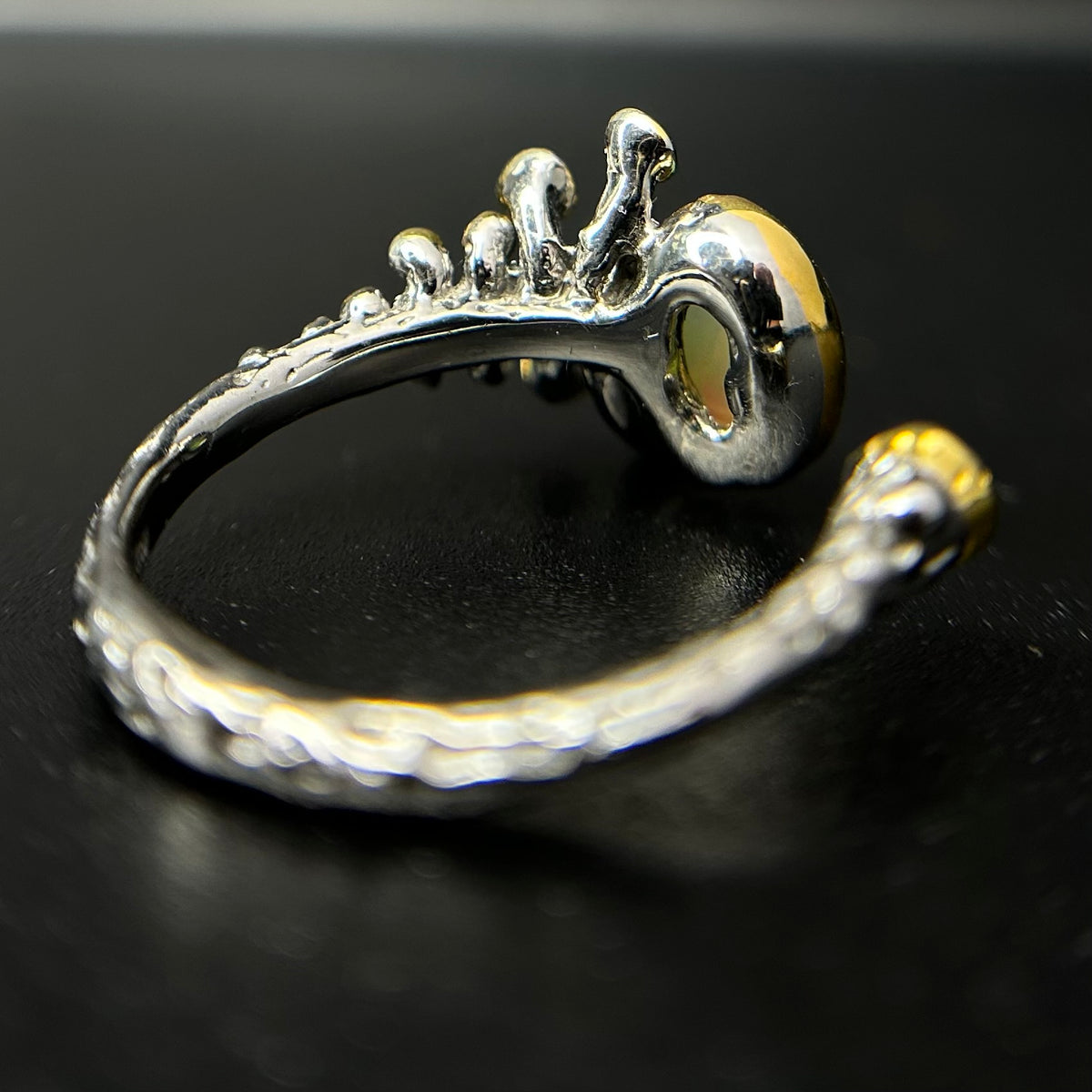 Silver ring with intricate design on a black background