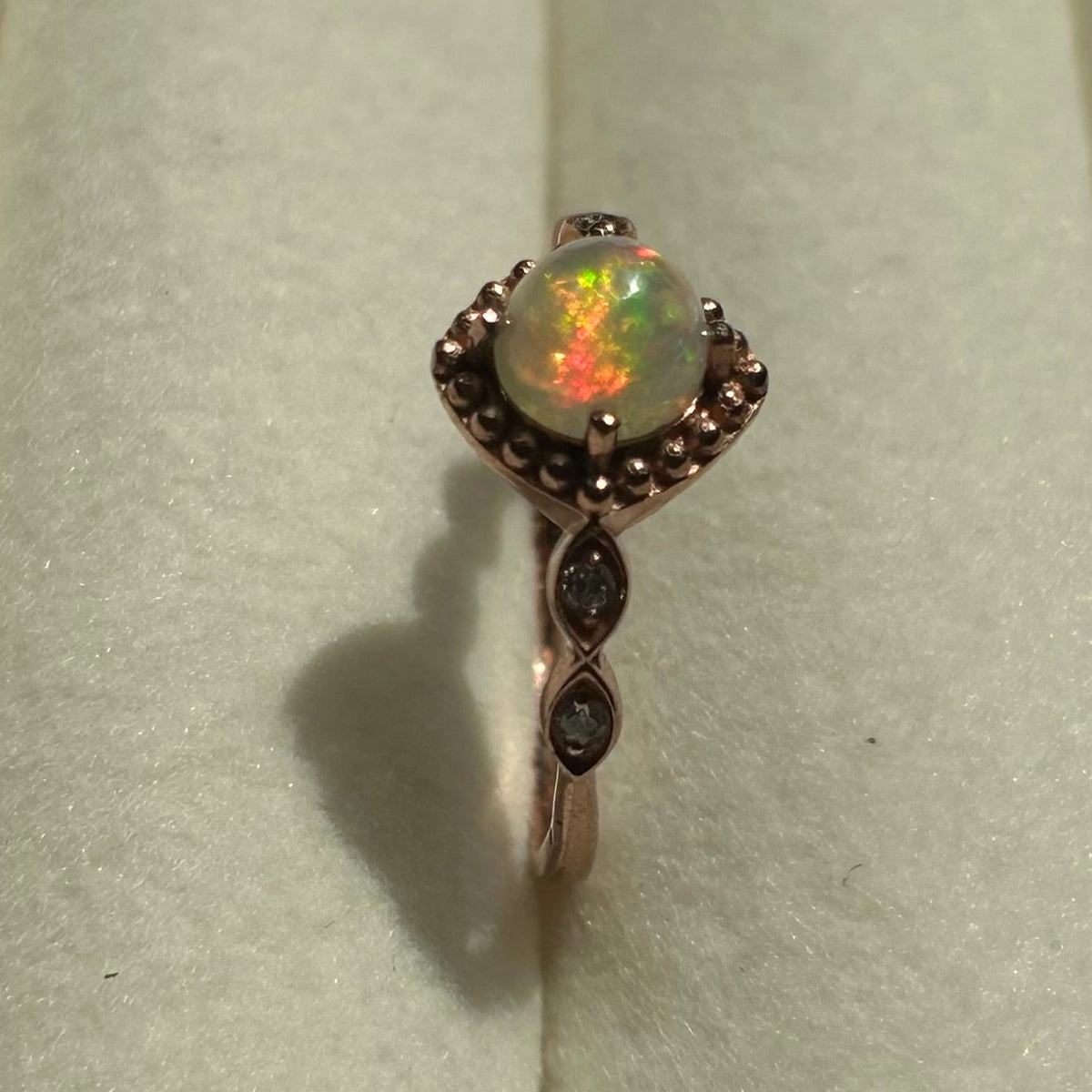 Silver ring with an opal stone on a light gray background