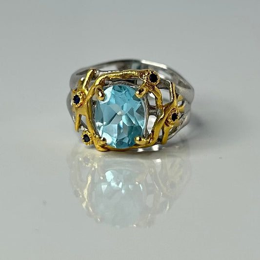 Ring with a blue topaz gemstone and gold accents on a gray background