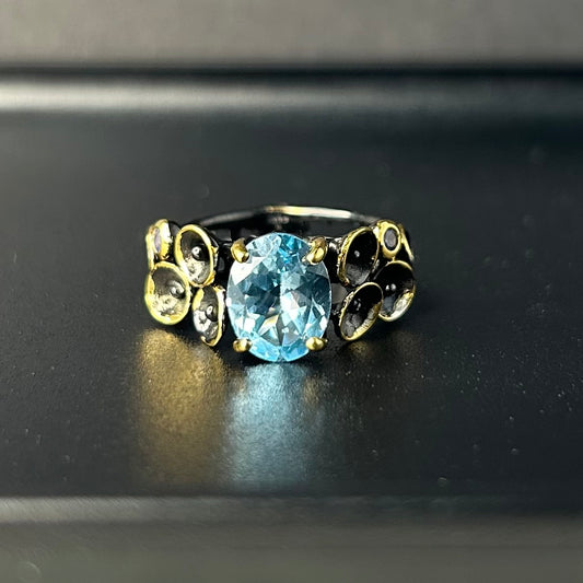 Ring with a blue gemstone and gold accents on a black background