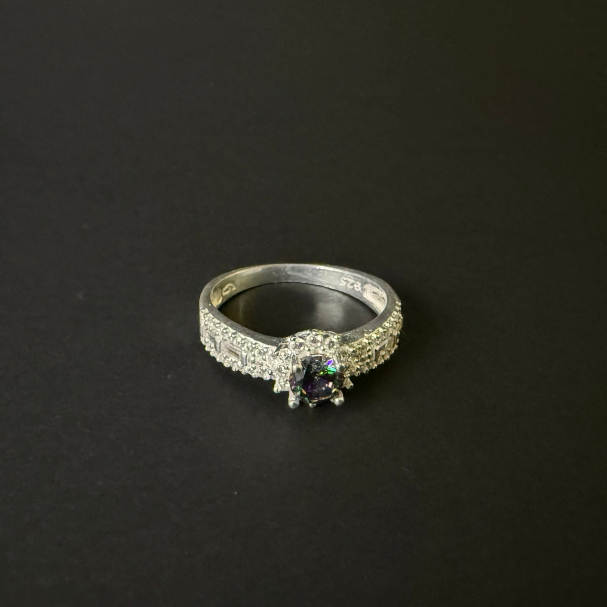 Silver ring with a colorful mystic quartz on a light purple background
