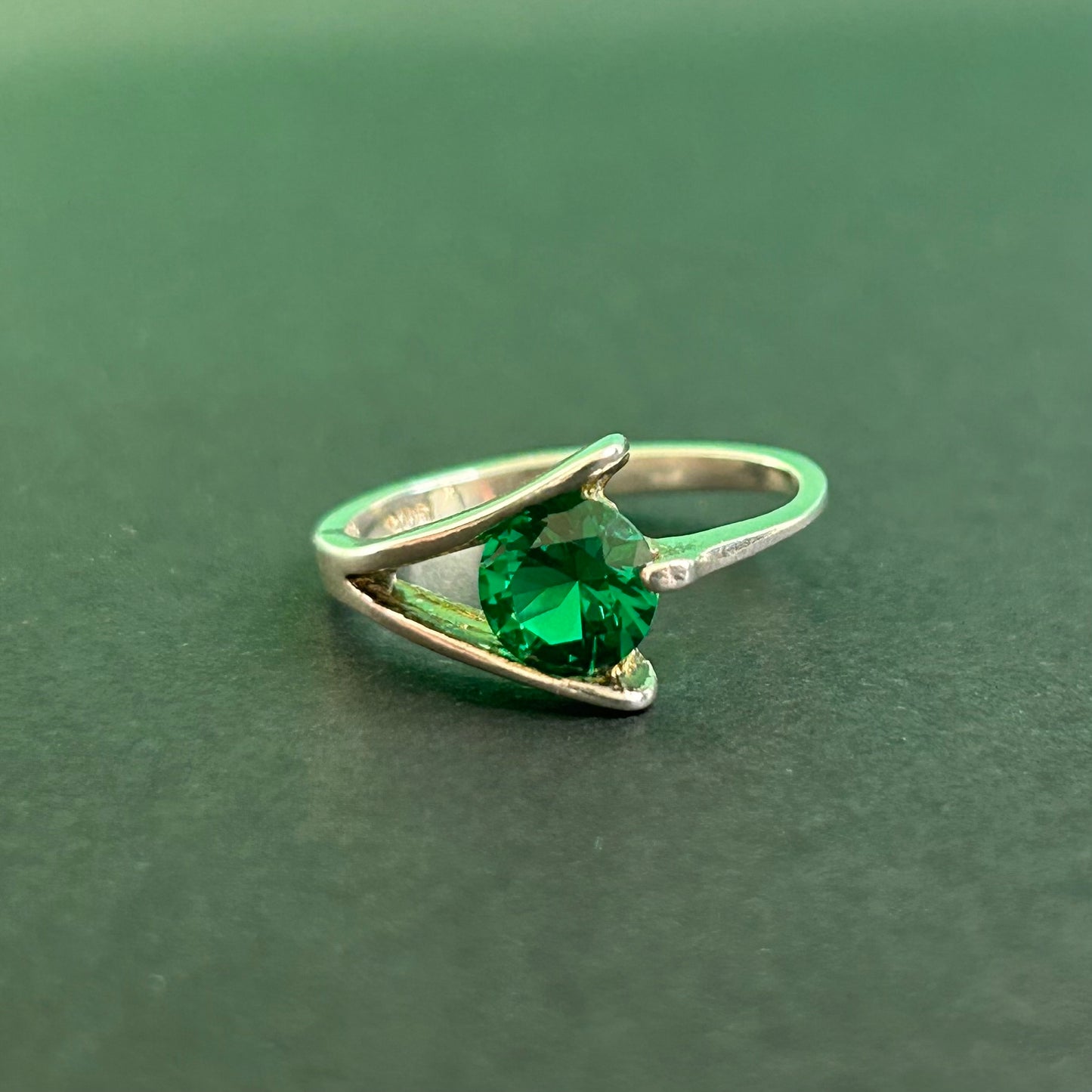 Silver ring with a green gemstone on a green background