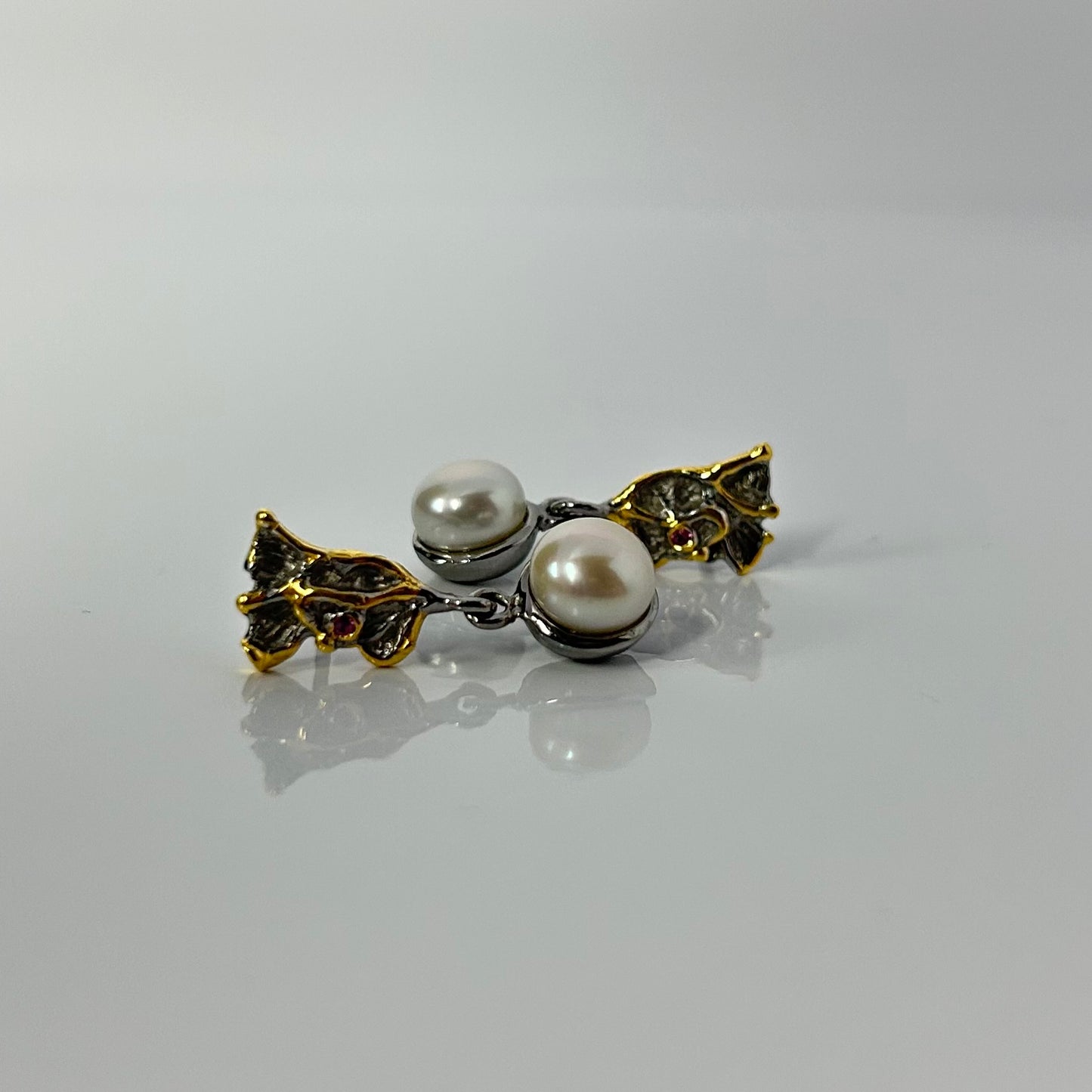Pearl earring with gold leaves on a gray background