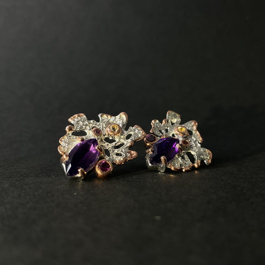 Silver earring with purple amethyst gemstones on a black background
