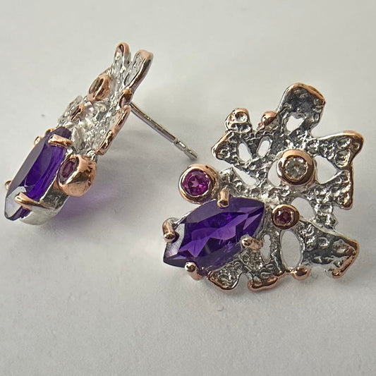 Silver earring with purple amethyst gemstones on a light background