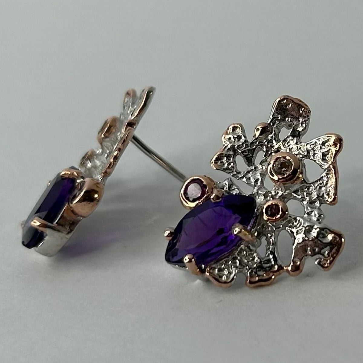 Silver earring with purple amethyst gemstones on a light background