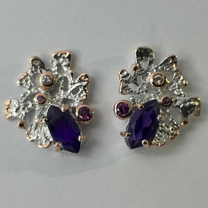 Pair of earrings with purple amethysts on a light gray background