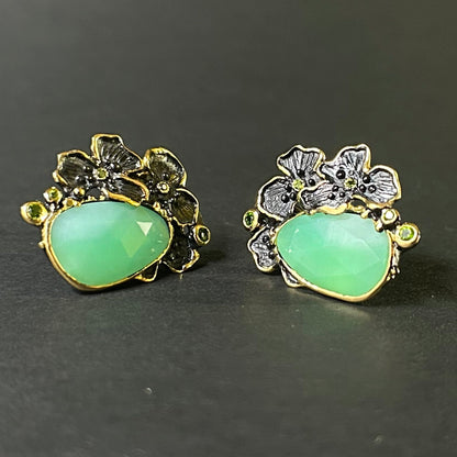 Pair of silver earrings with green chrysoprase gemstones and floral designs on a gray background
