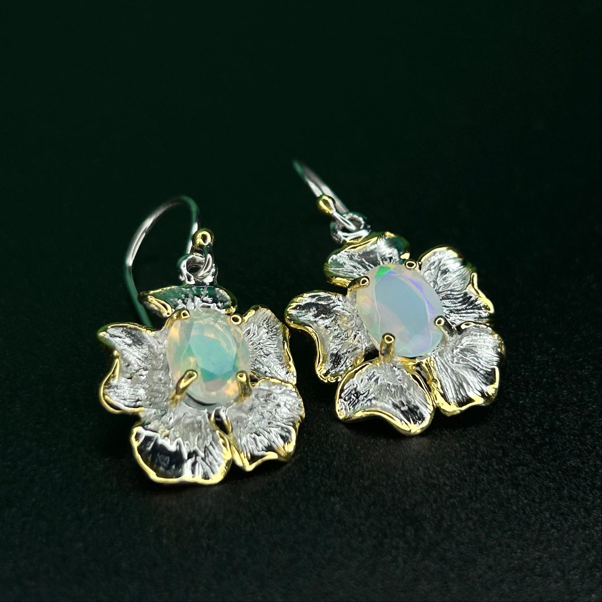 Floral earrings with Ethiopian opal stones on a black background