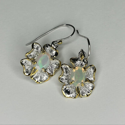 Pair of floral earrings with gemstones on a gray background