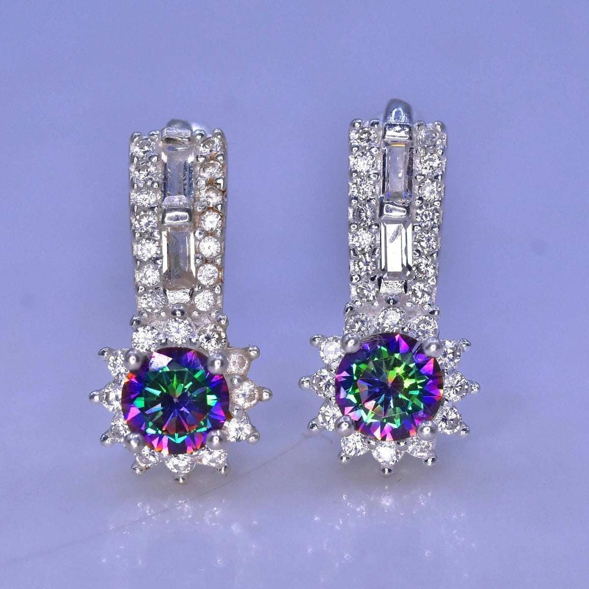 Pair of silver earrings with colorful mystic quartz on a light purple background