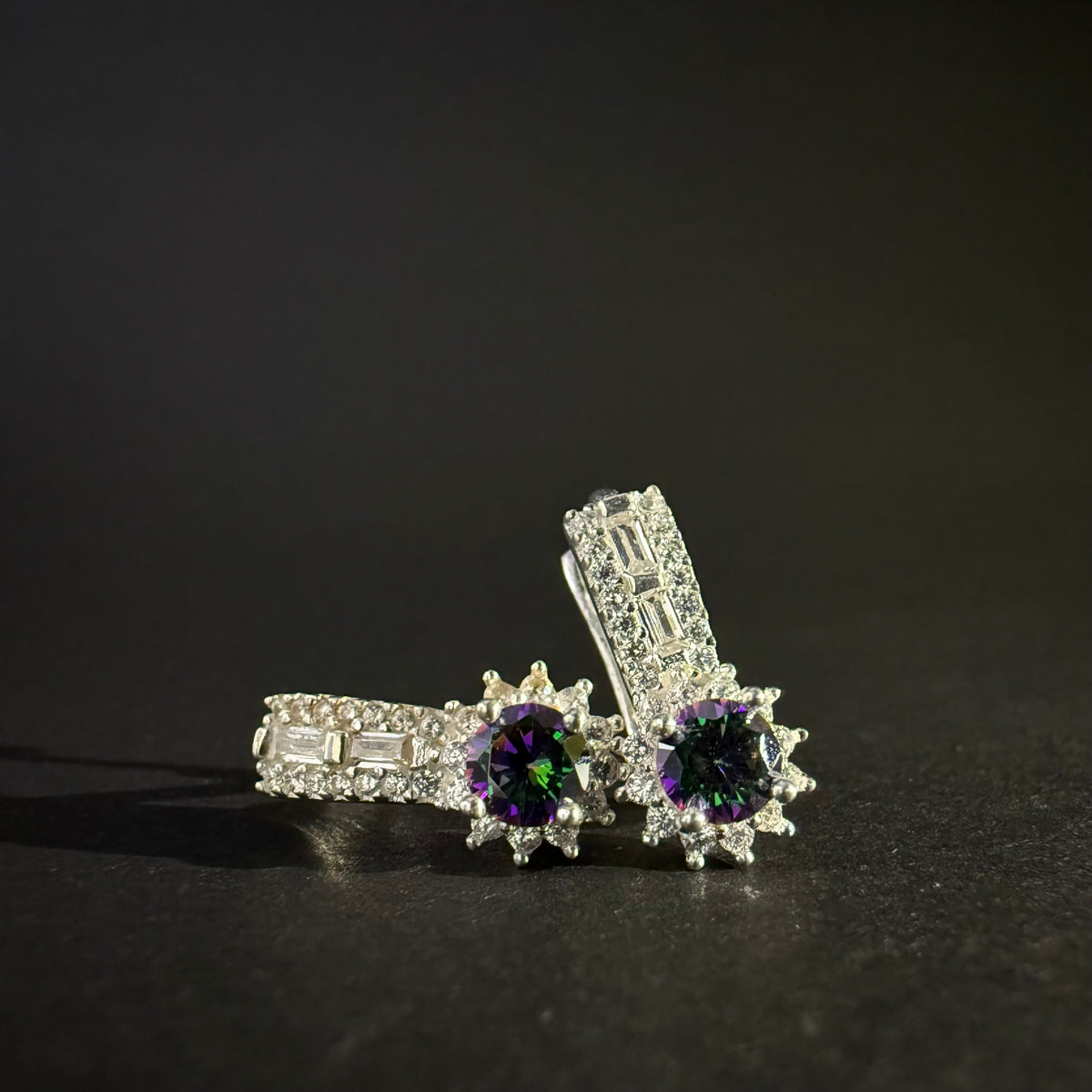 Pair of silver earrings with colorful mystic quartz on a light purple background