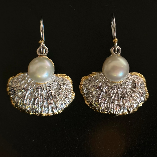 Pair of silver gold earrings with pearl beads on a black background