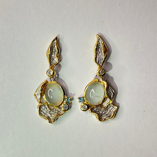 Pair of silver gold earrings with gemstones on a light gray background