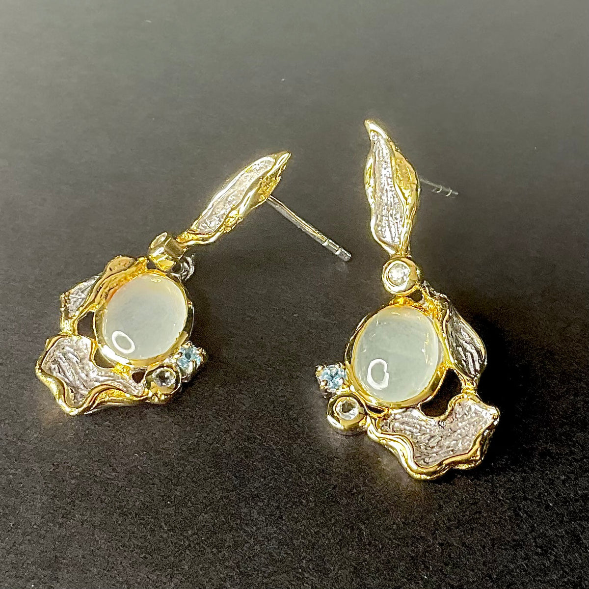Silver earrings with a central gemstone on a dark background