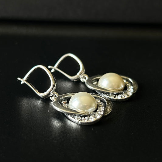 Silver earrings with pearls on a black background
