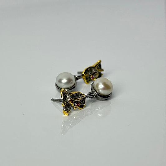 Pair of pearl earrings with gold accents on a light gray background