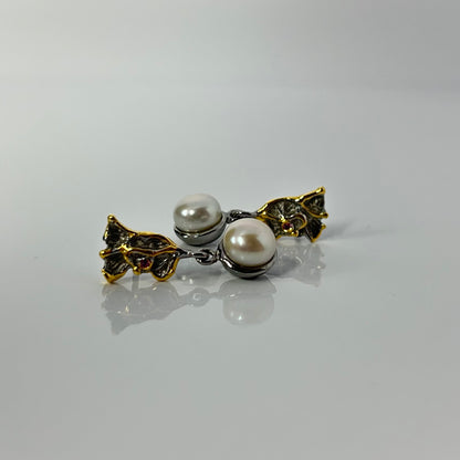 Pearl earring with gold leaves on a gray background