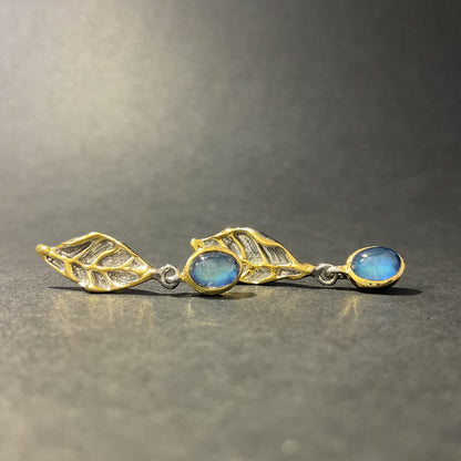 Silver and gold earrings with blue stones on a gray background