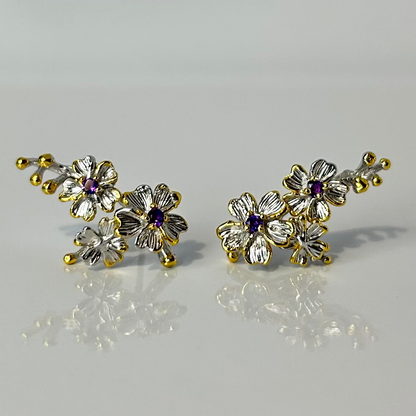 Pair of floral earrings with gold and silver accents on a light gray background