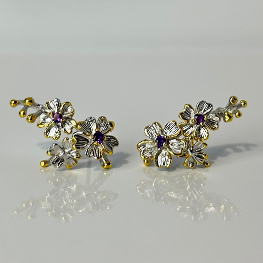Pair of floral earrings with gold and silver accents on a light gray background