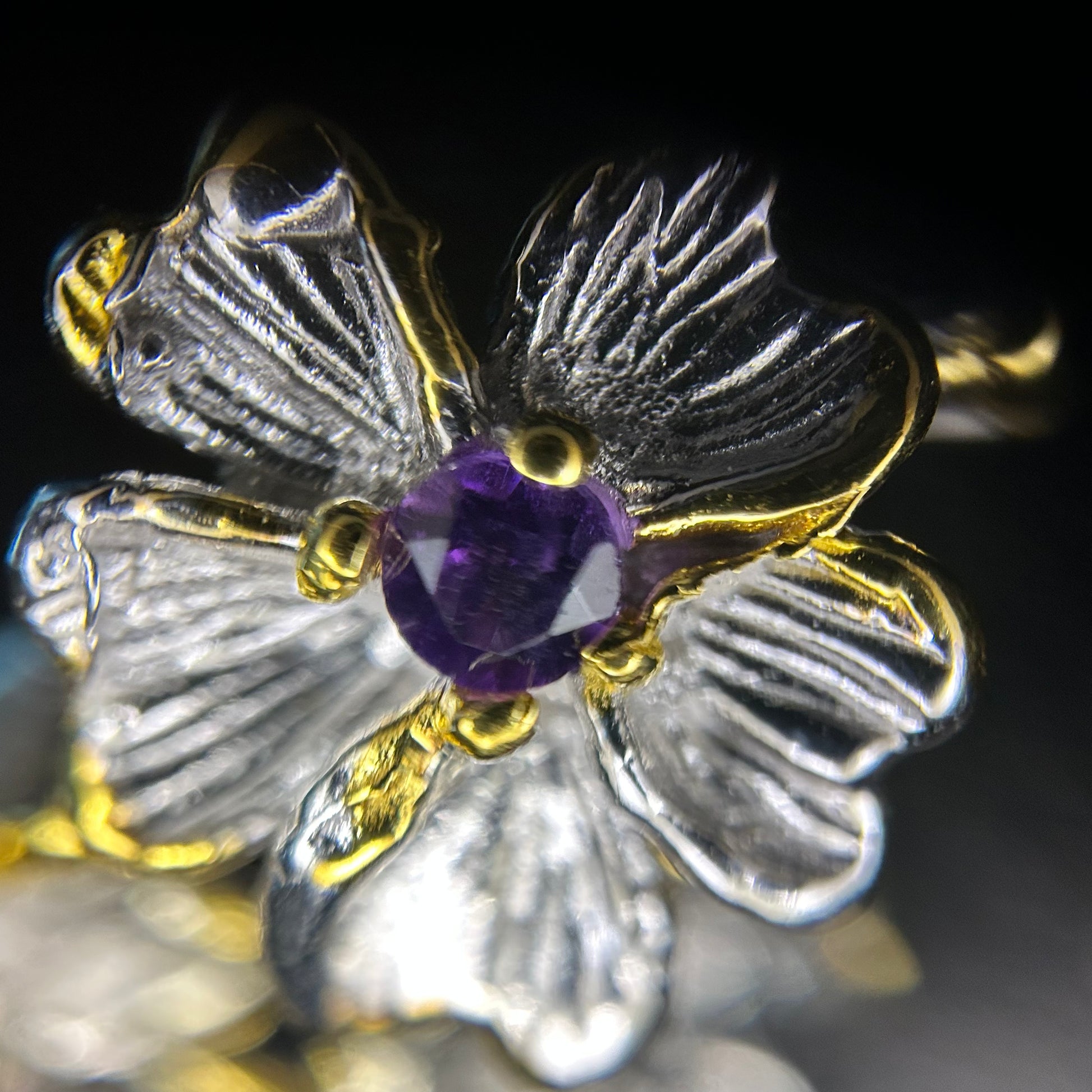 Close-up of a flower in a silver and gold earring featuring an amethyst