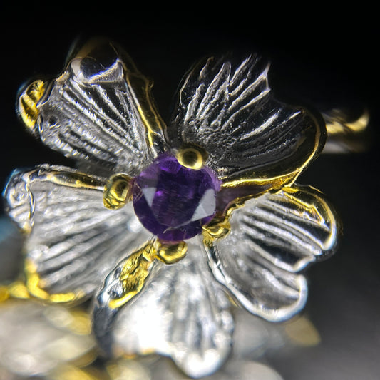 Close-up of a flower in a silver and gold earring featuring an amethyst
