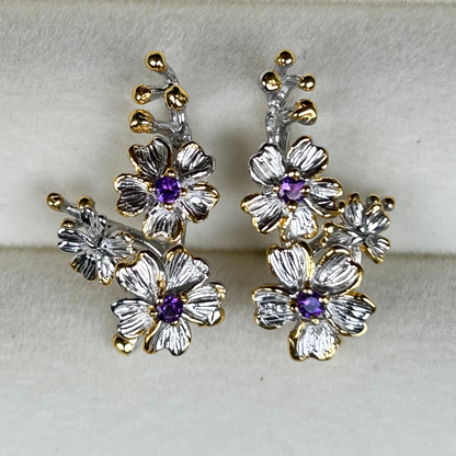 Pair of floral earrings with gold and silver accents on a light gray background
