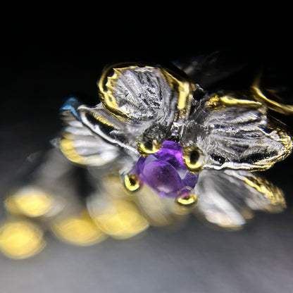 Close-up of a flower in a silver and gold earring featuring an amethyst