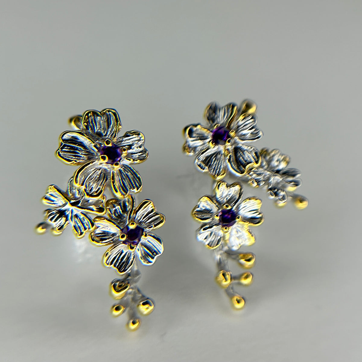 Floral earrings with gold and silver accents on a gray background
