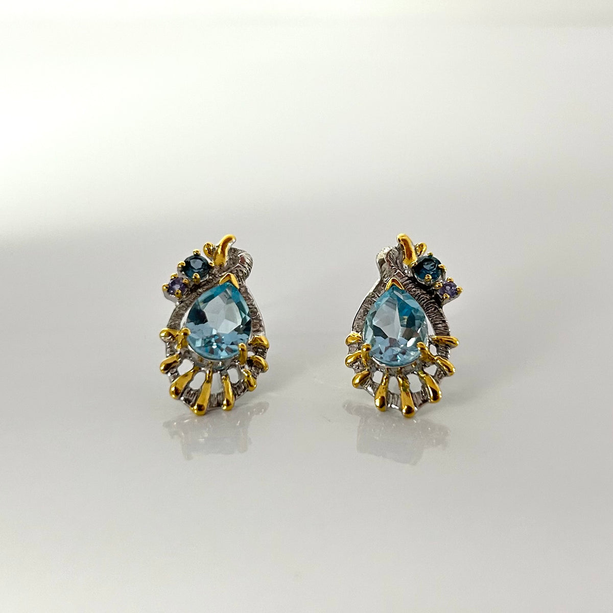Pair of gold and topaz earrings on a light gray background
