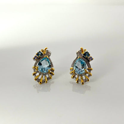 Pair of gold and topaz earrings on a light gray background