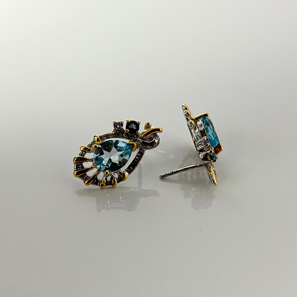 Pair of earrings with blue topaz on a light gray background