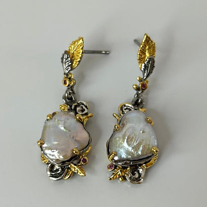 Pair of gold and silver earrings with keshi pearls gemstones on a gray background