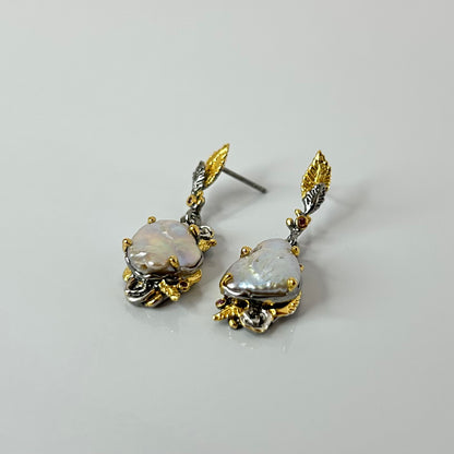 Pair of gold and silver earrings with keshi pearl stones on a light gray background