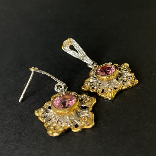 Pair of gold and silver earrings with pink tourmaline gemstones on a black background