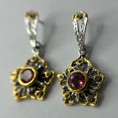 Pair of ornate silver earrings with tourmaline gemstones on a gray background