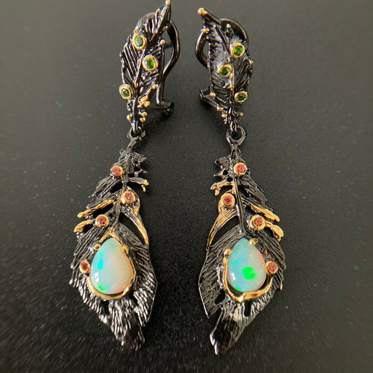 Pair of feather-shaped earrings with gemstones on a dark background