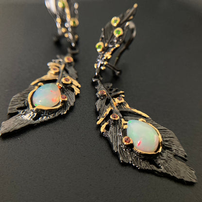 Feather-shaped earrings with opal stones on a black background