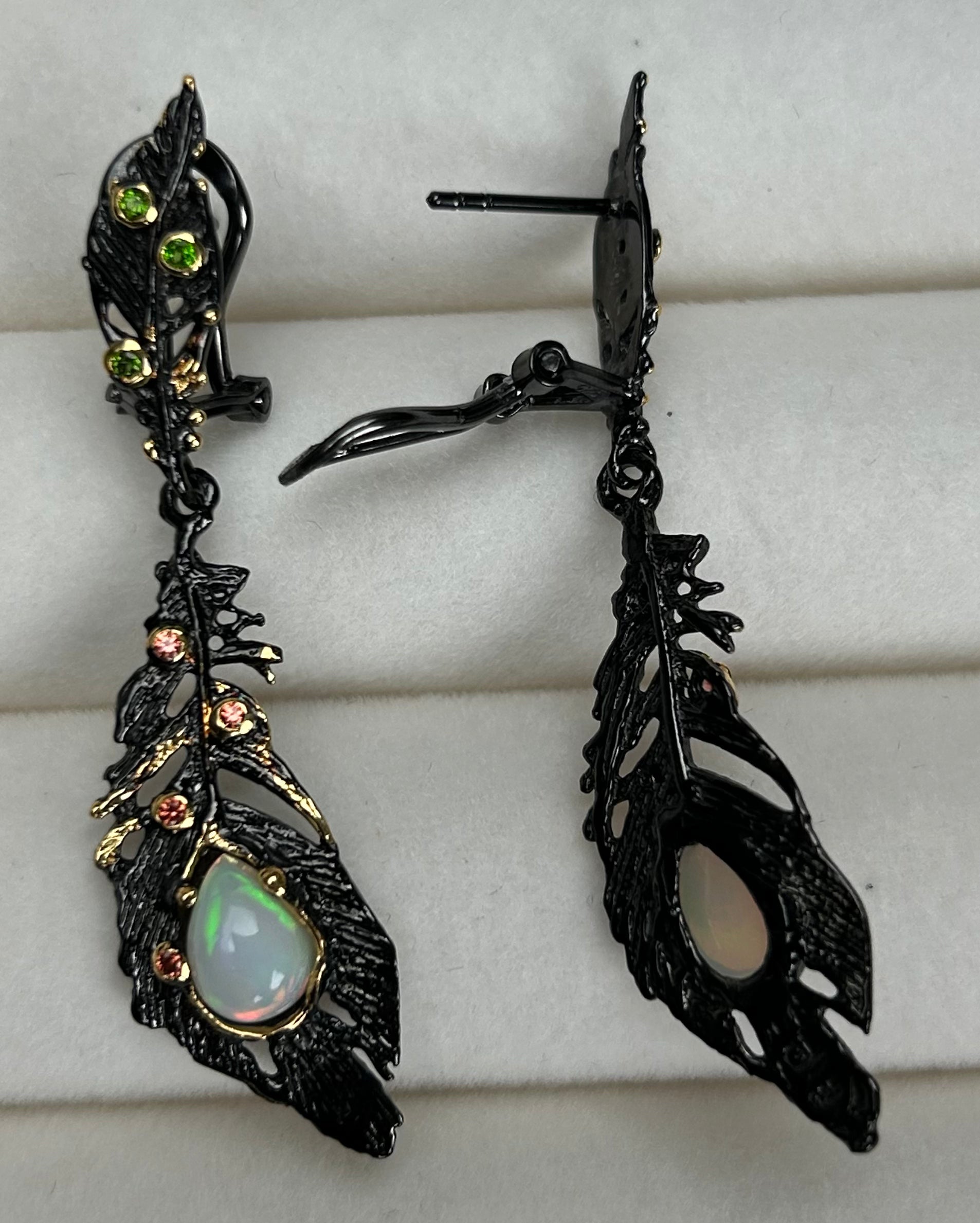 Ornate black feather earrings with a central gemstone on a white background