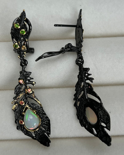 Ornate black feather earrings with a central gemstone on a white background