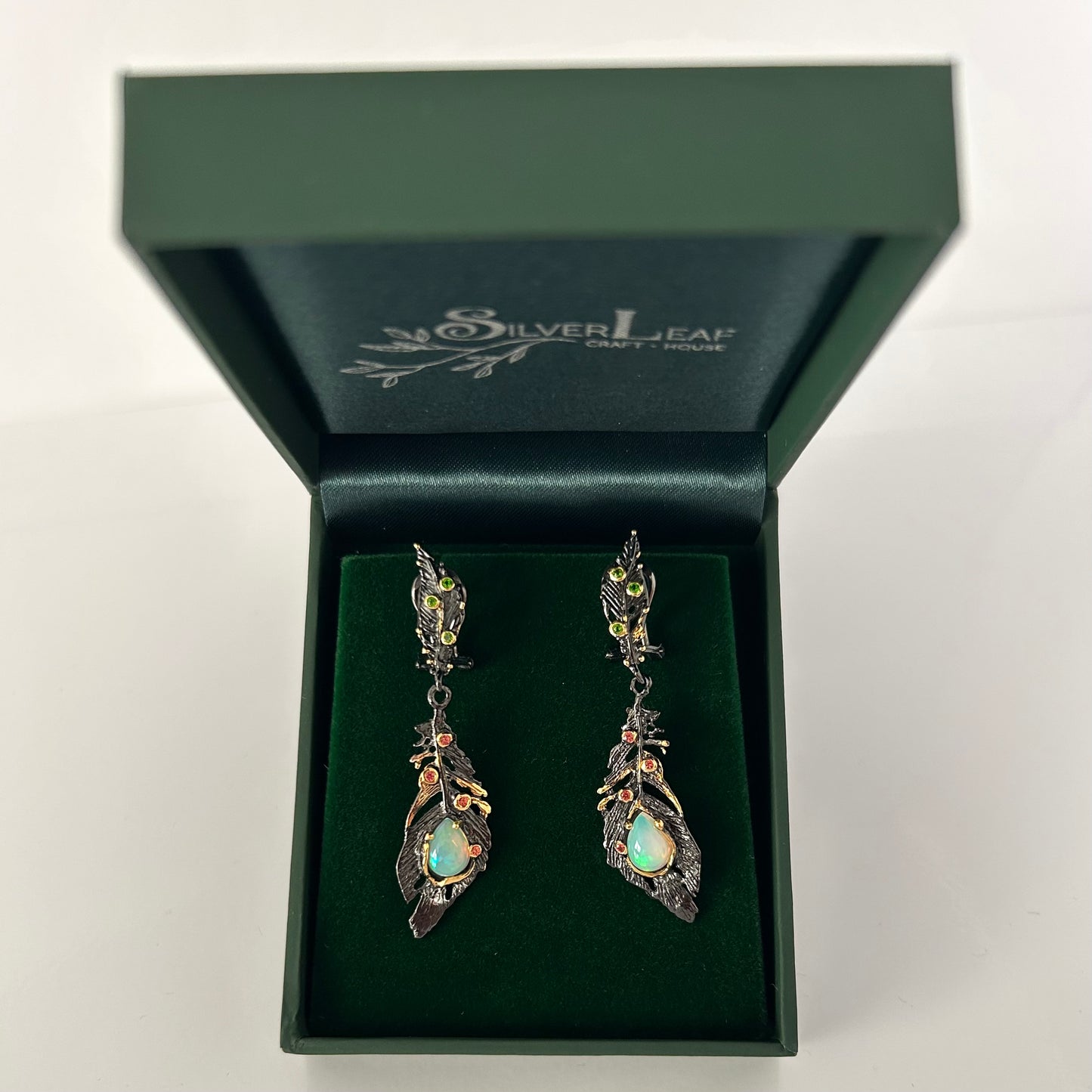 Pair of silver earrings with green gemstones in a Silverleaf craft house box.