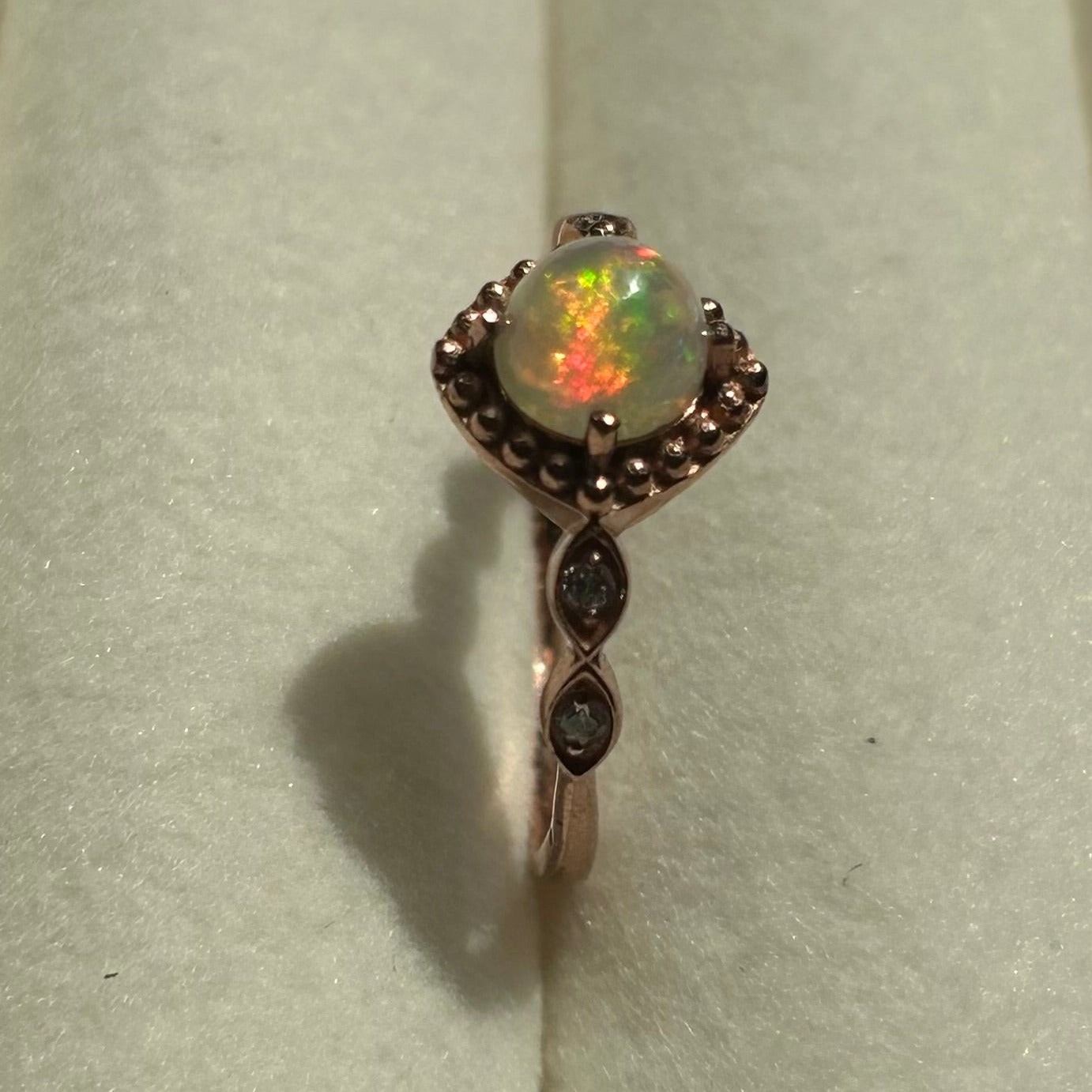 Silver ring with an opal stone on a light gray background